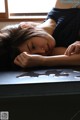 A woman laying on a table with her head on her hands.