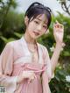 A woman in a pink hanbok poses for a picture.