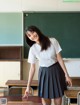 A woman in a school uniform standing in front of a blackboard.