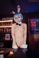 A naked woman in bunny ears sitting at a bar.