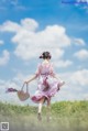 A woman in a pink dress is walking in a field.