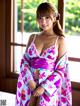 A woman in a pink and white kimono posing for a picture.