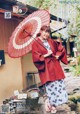 A woman in a red kimono holding an umbrella.