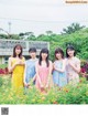 A group of young women standing in a field of flowers.