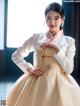 A woman in a white and pink hanbok is posing for a picture.