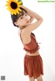 A young girl holding a sunflower in her hair.