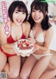 A couple of women sitting next to each other holding a cake.