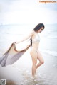 A woman in a white bikini standing on the beach.