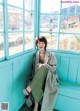 A woman sitting on a bench in front of a window.