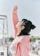 A woman in a pink hoodie standing on top of a building.